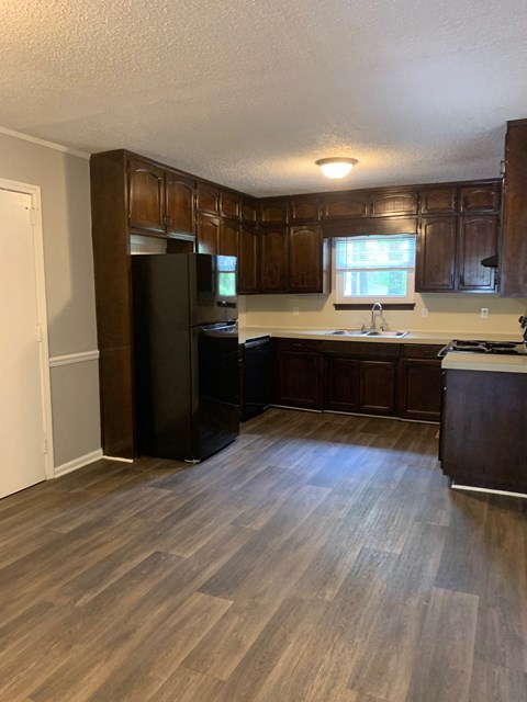 A kitchen with wooden cabinets and a black refrigerator.