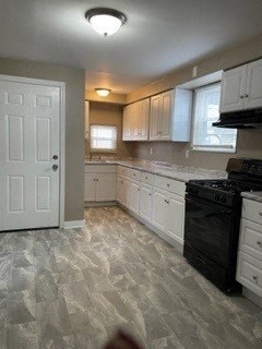 A kitchen with a black stove top oven and white cabinets.
