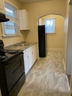 A kitchen with a black stove top oven and white cabinets.