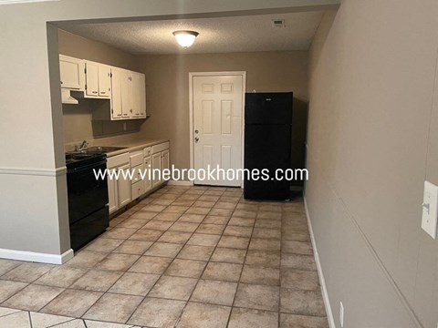 A kitchen with a black fridge and white cabinets.