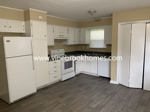a small kitchen with white cabinets and a stove and refrigerator