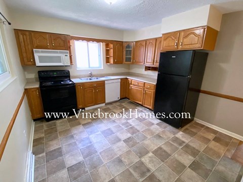 A kitchen with wooden cabinets and black appliances.