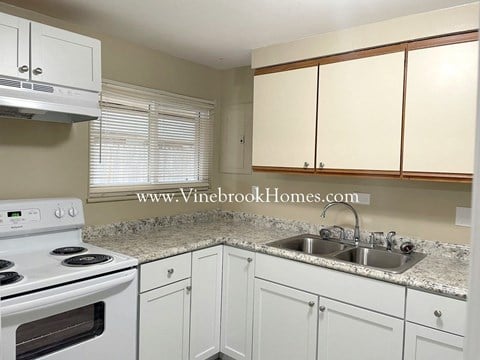 a small kitchen with white cabinets and a sink and a stove