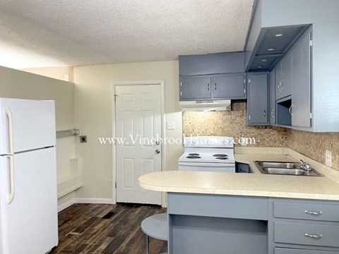 a kitchen with blue cabinets and white appliances and a counter top