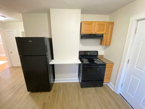 a kitchen with a black stove and refrigerator and wooden cabinets