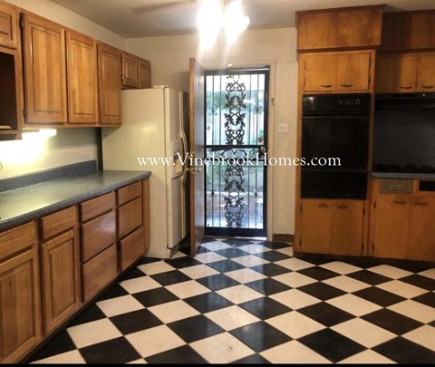 a kitchen with a checkered floor and wooden cabinets