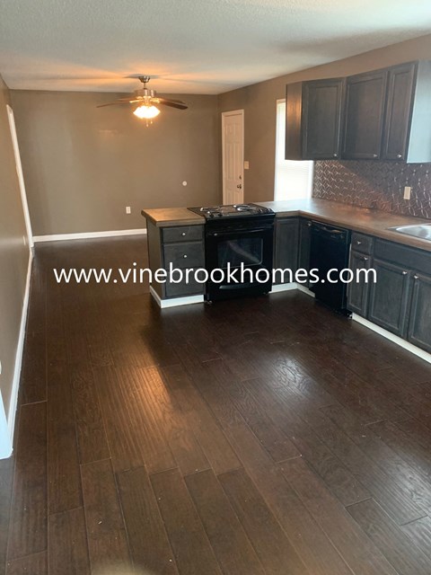 A kitchen with dark wood floors and black cabinets.