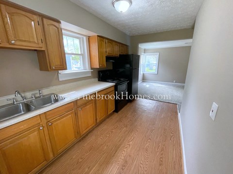 a small kitchen with wood floors and wooden cabinets and a black stove