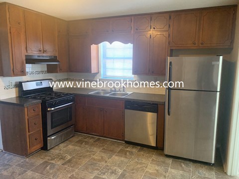 A kitchen with wooden cabinets and a stainless steel refrigerator.