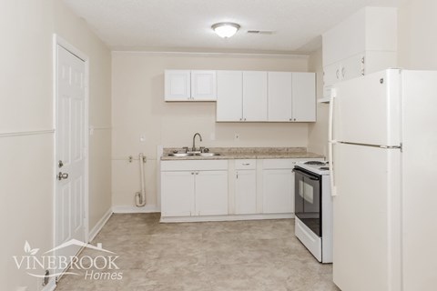a kitchen with white cabinets and a refrigerator and a sink