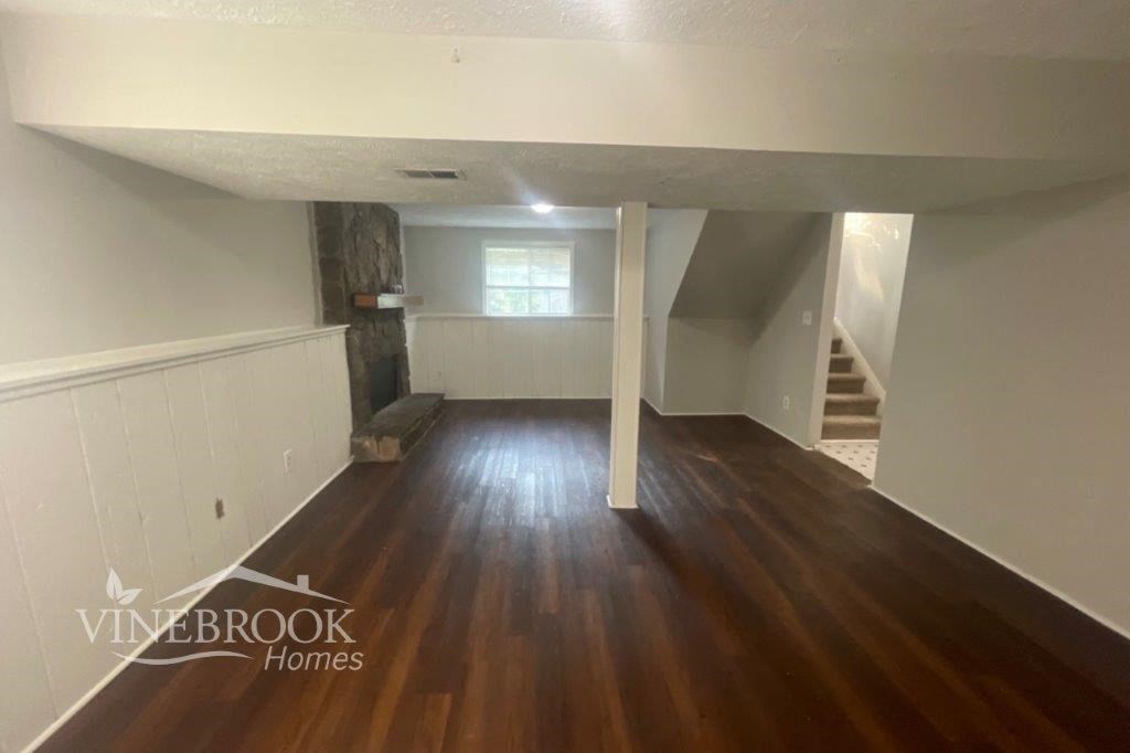 a living room with wood floors and white walls and a staircase