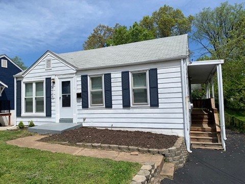 a small white house with a front yard and steps