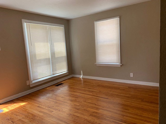 an empty room with a hard wood floor and two windows