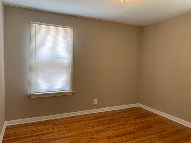 an empty room with a window and wooden floors