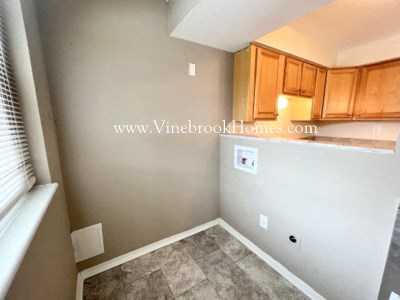 a look at the corner of a small room with wooden cabinets and a window