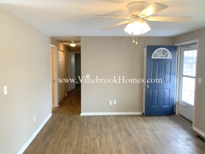 an empty living room with a ceiling fan and a blue door