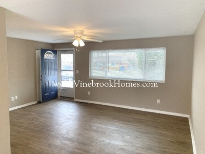 an empty living room with a ceiling fan and a window