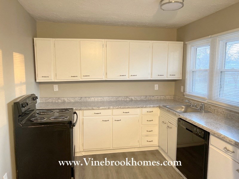 A kitchen with white cabinets and a black stove top oven.