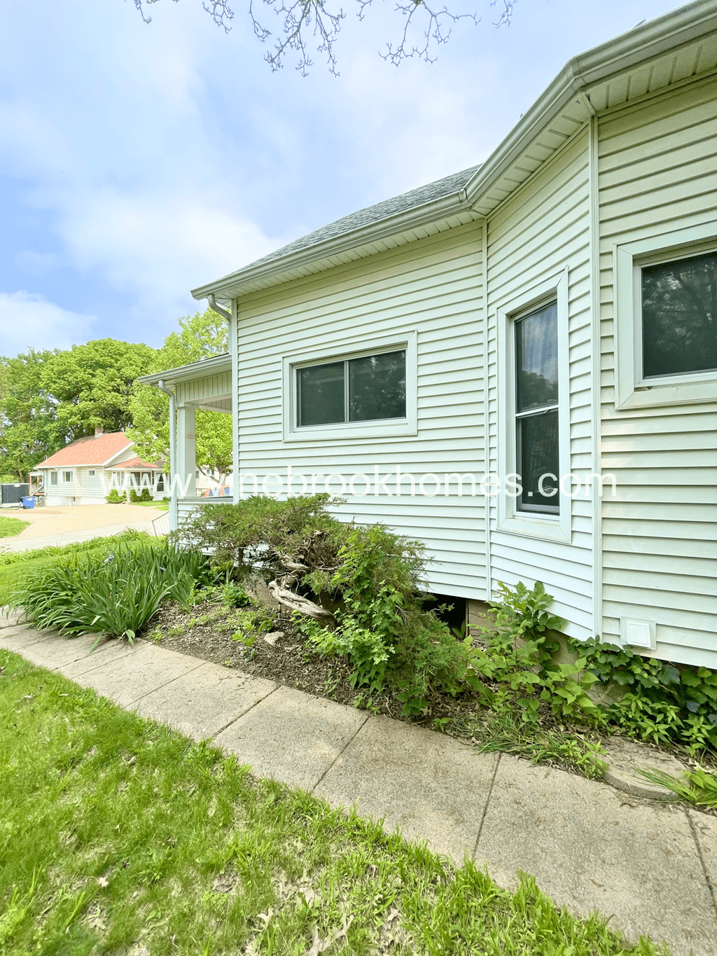 a side view of a white house with a garden next to it