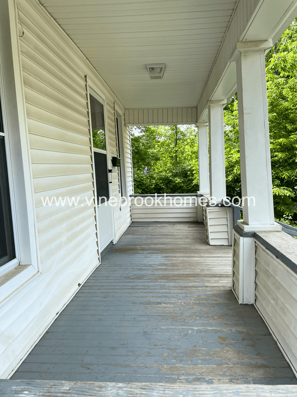 the covered porch of an old with a porch swing