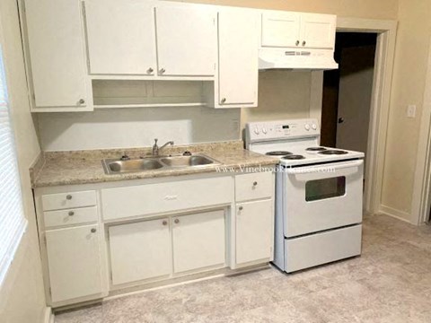 A kitchen with white cabinets and a white stove top oven.
