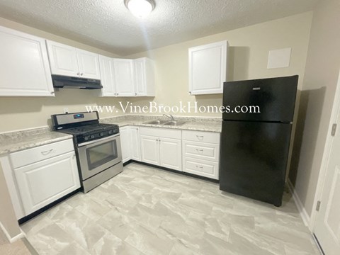 A kitchen with white cabinets and a black refrigerator.