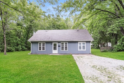 a blue house with a yard and a driveway