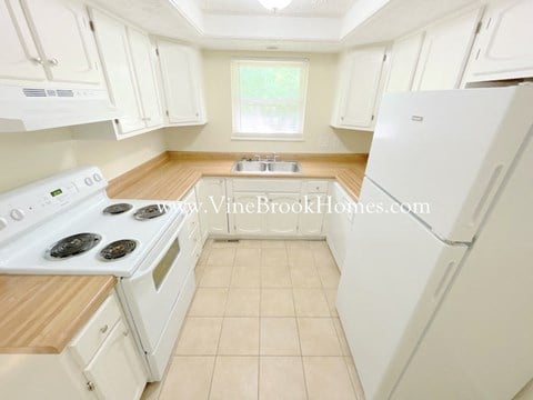 A kitchen with white appliances and wooden countertops.