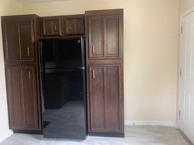 a kitchen with wooden cabinets and a black refrigerator