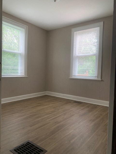 an empty room with a wood floor and two windows