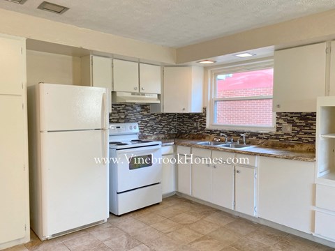 a kitchen with white cabinets and a refrigerator and a sink