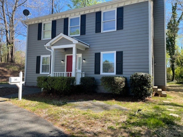 a gray house with a red door and a white mailbox