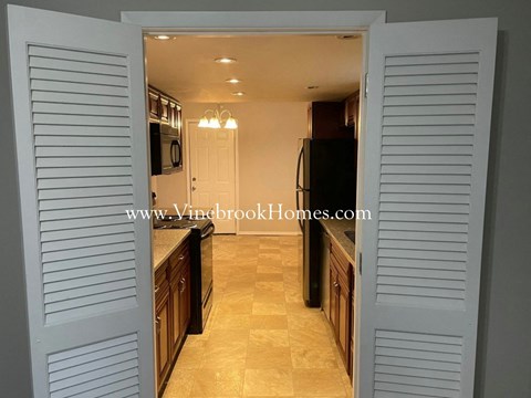 A kitchen with a black refrigerator and wooden cabinets.