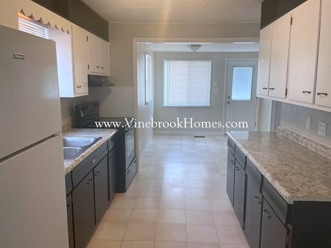A kitchen with black cabinets and a white fridge.
