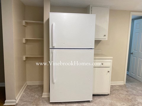 A white refrigerator in a kitchen with a website address on the wall.