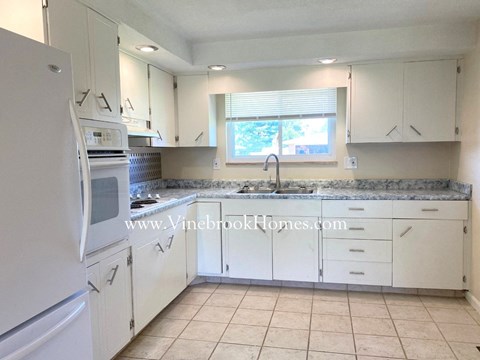 A kitchen with white appliances and cabinets.