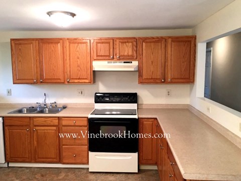 A kitchen with wooden cabinets and a white stove top oven.