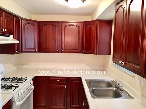 A kitchen with wooden cabinets and a stove top oven.