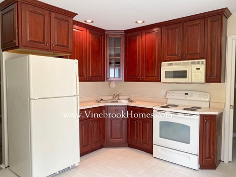A kitchen with brown cabinets and white appliances.