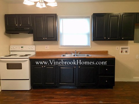 a kitchen with black cabinets and white appliances and a window