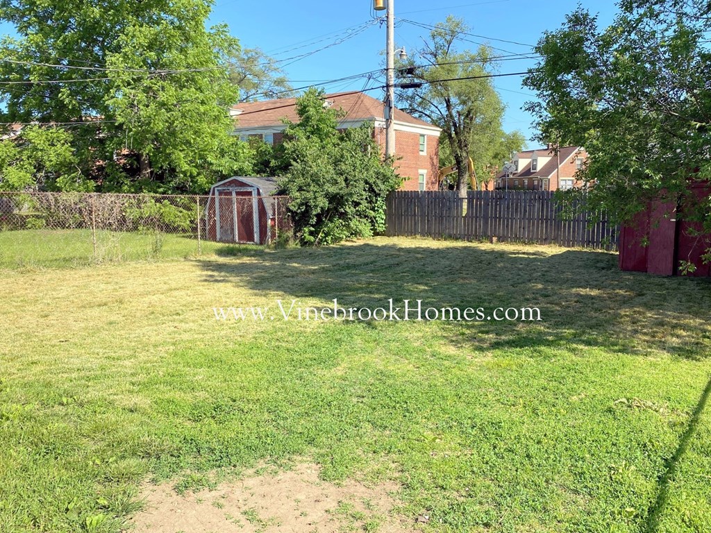 a backyard with a fence and a shed in the yard