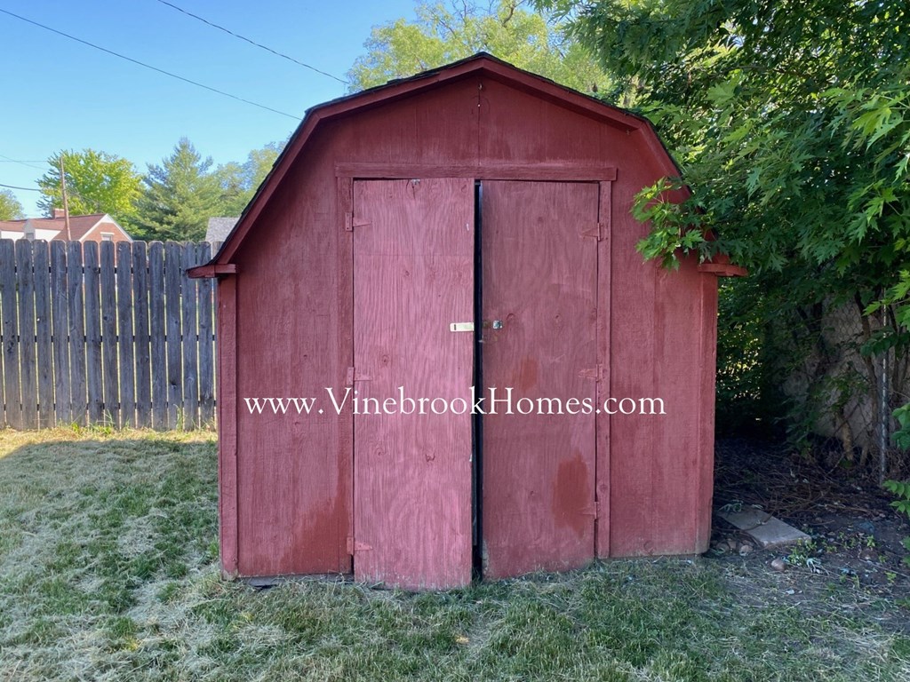 a small red shed in front of a fence