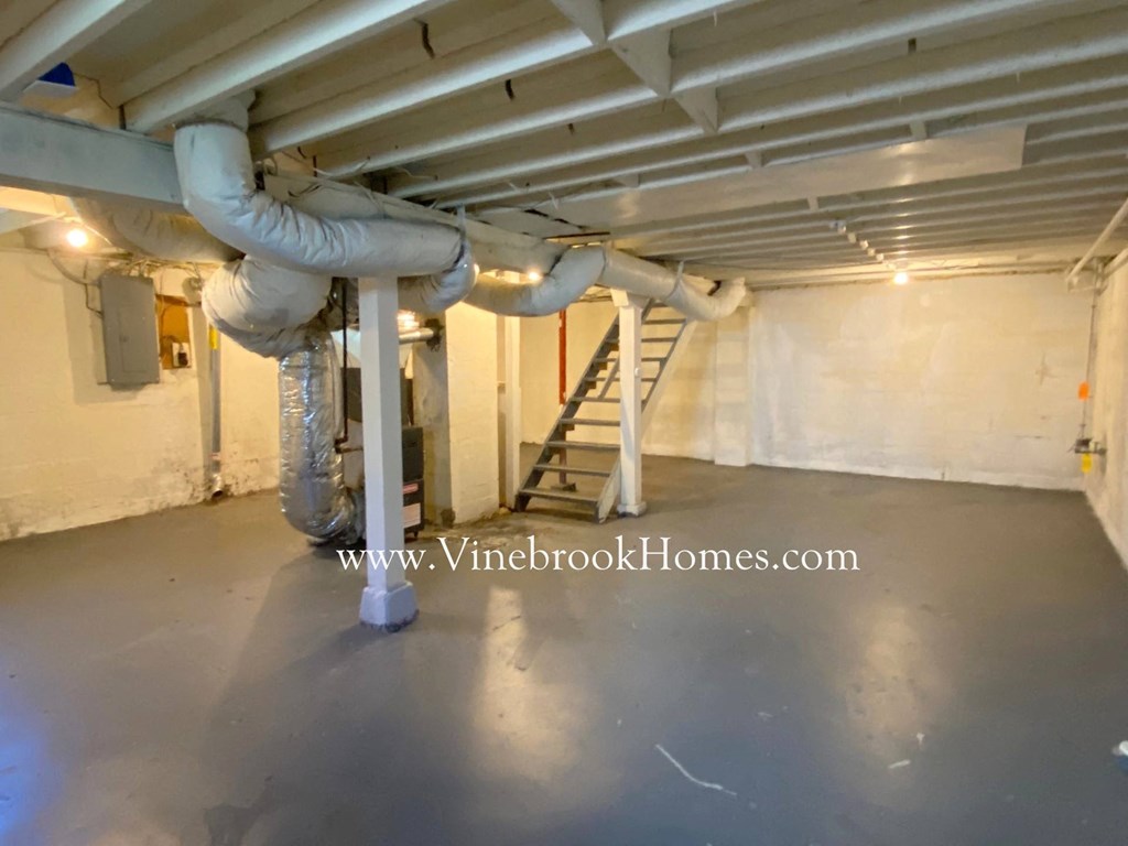 the underground basement of a building with pipes and a staircase