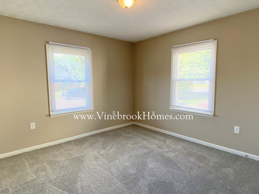 a bedroom with two windows and a carpeted floor