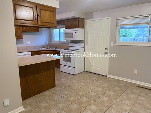a small kitchen with a white stove and microwave and wooden cabinets