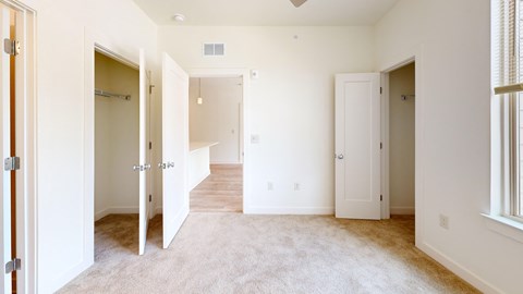 A spacious room with white walls and carpeted floor.