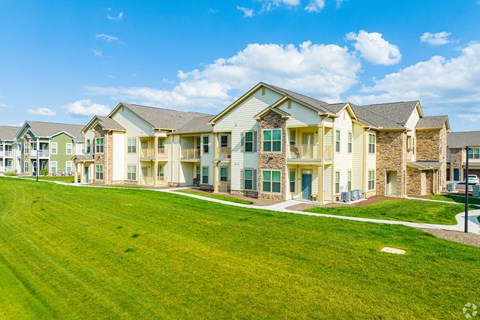 an apartment building with a green lawn in front of it