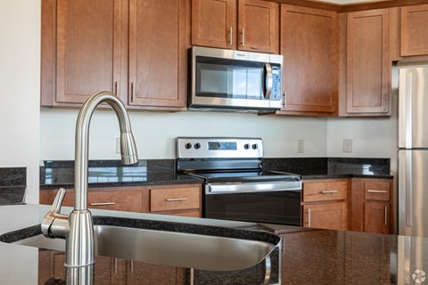 A kitchen with brown cabinets and a black countertop.
