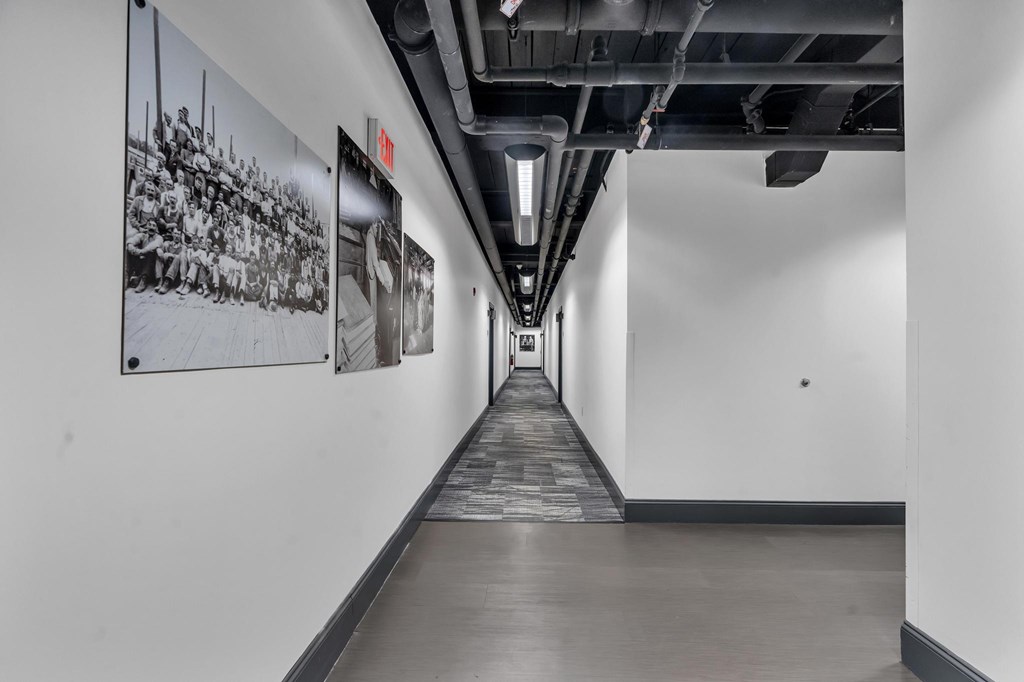 A long hallway with a black and white picture on the wall.
