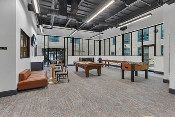 A room with a carpeted floor and a variety of seating options including a couch, chairs, and a table.